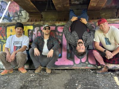 Three band members sitting on their haunches, a fourth band member hanging upside down.