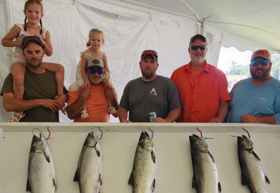 Five men (two with little girls upon their shoulders) stand behind fish caught in derby.