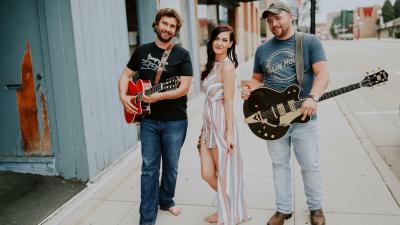 Three members of Nettle Hill standing on sidewalk.