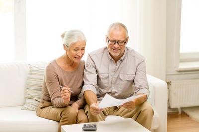 Elderly couple sitting next to each other on the couch looking at a piece of paper