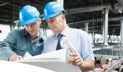 Two men looking at plans wearing blue hard hats