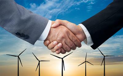 Two men's arms shown shaking hands. In the background are windmills in front of a sunset