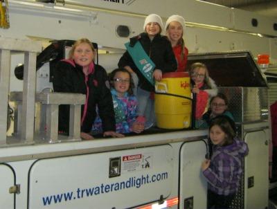 Girls standing on and around work truck that reads www.trwaterandlight.com