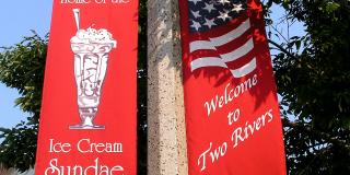 Two red pole banners, one that says Welcome to Two Rivers, the other says Home of the Ice Cream Sundae