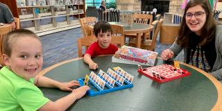 A family of a woman and two young boys playing a game in Lester Public Library
