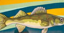 A mural painted on brick of a green fish on a blue, green, and yellow background