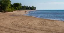 Sandy beach at Lake Michigan with a person walking on the beach in the distance