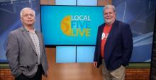 Two men standing in front of a television that says Local Five Live