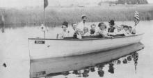 A black and white photo of several people in a boat on the river