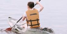 A person in a brown life vest kayaking in a sit-on-top kayak