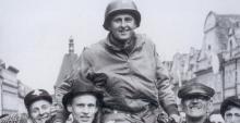 A black and white photo of Lt. Col. Matt Konop hoisted on the shoulders of a crowd