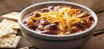 A bowl of chili with crackers on the side.
