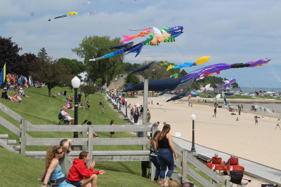 Spectators along the lakeshore and giant kites hovering over the beach.
