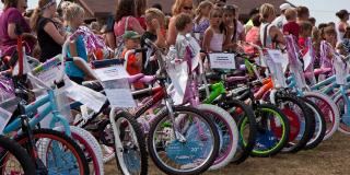A row of new bikes being looked over by children.
