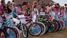 A row of new bikes being looked over by children.